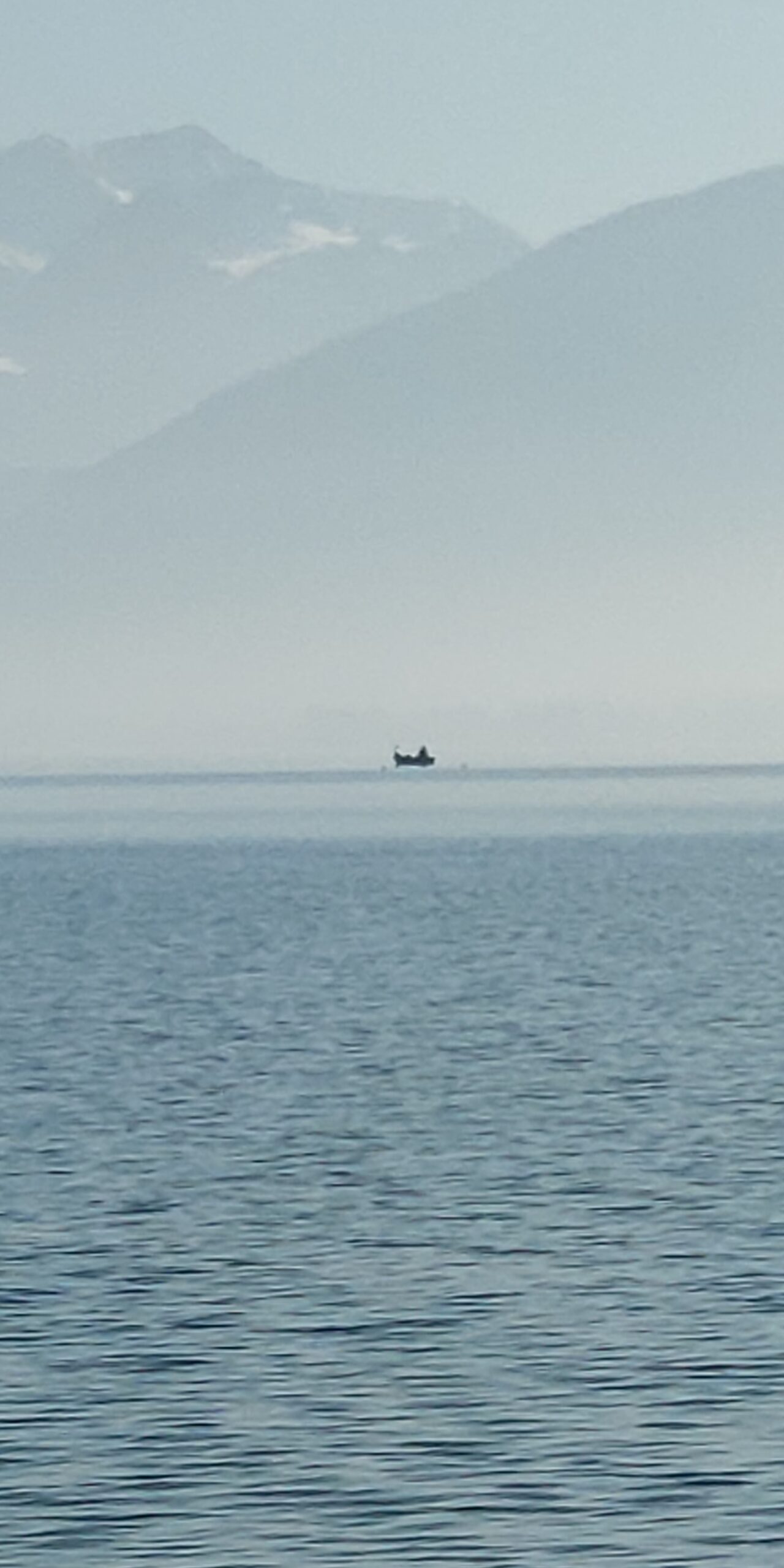 Petite barque isolée sur le lac d’Annecy noyé dans la brume.