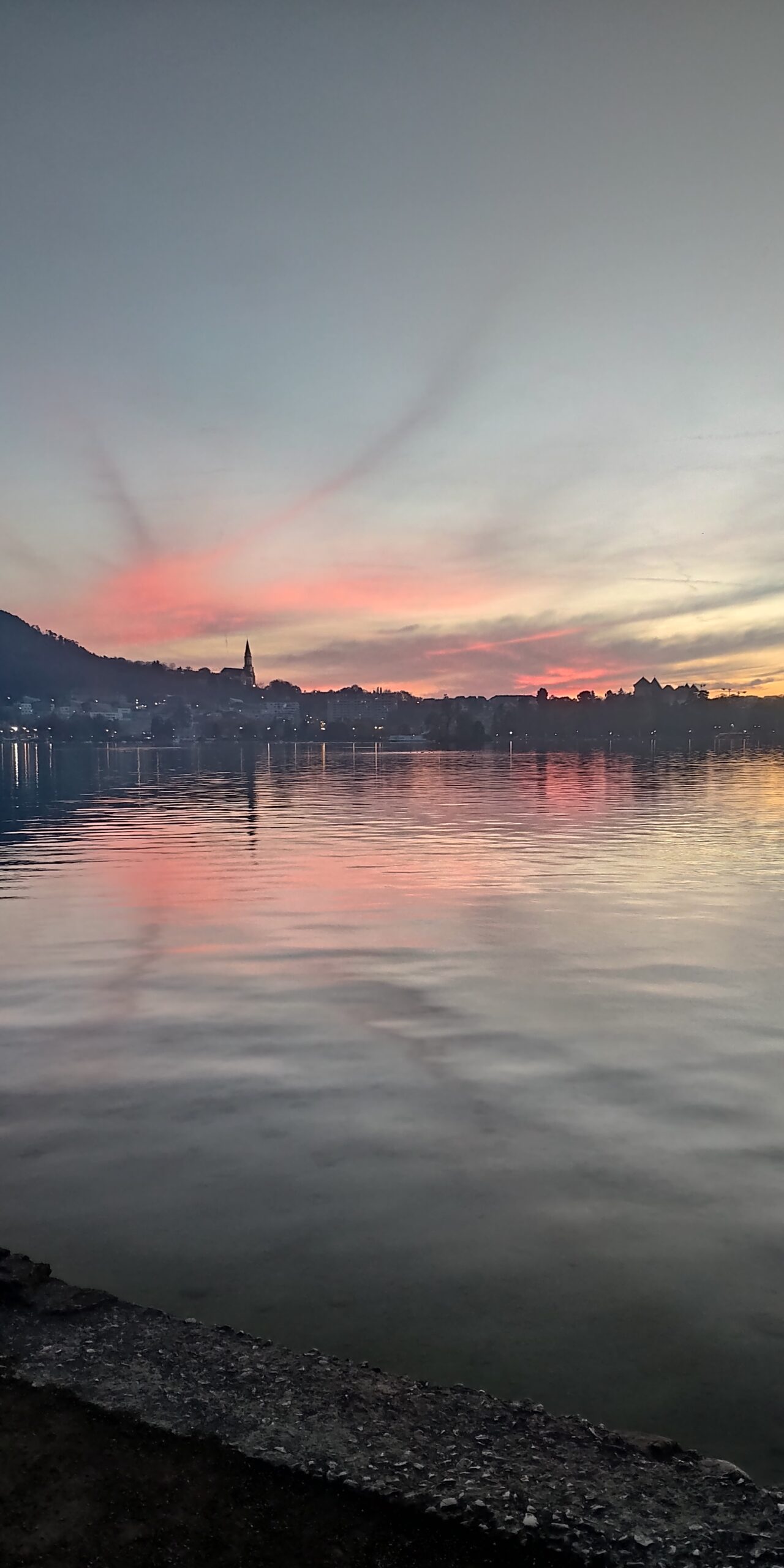 Ciel rose se reflétant sur le lac d’Annecy au crépuscule.