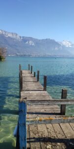Ponton en bois avançant dans l’eau claire et turquoise du lac d’Annecy.