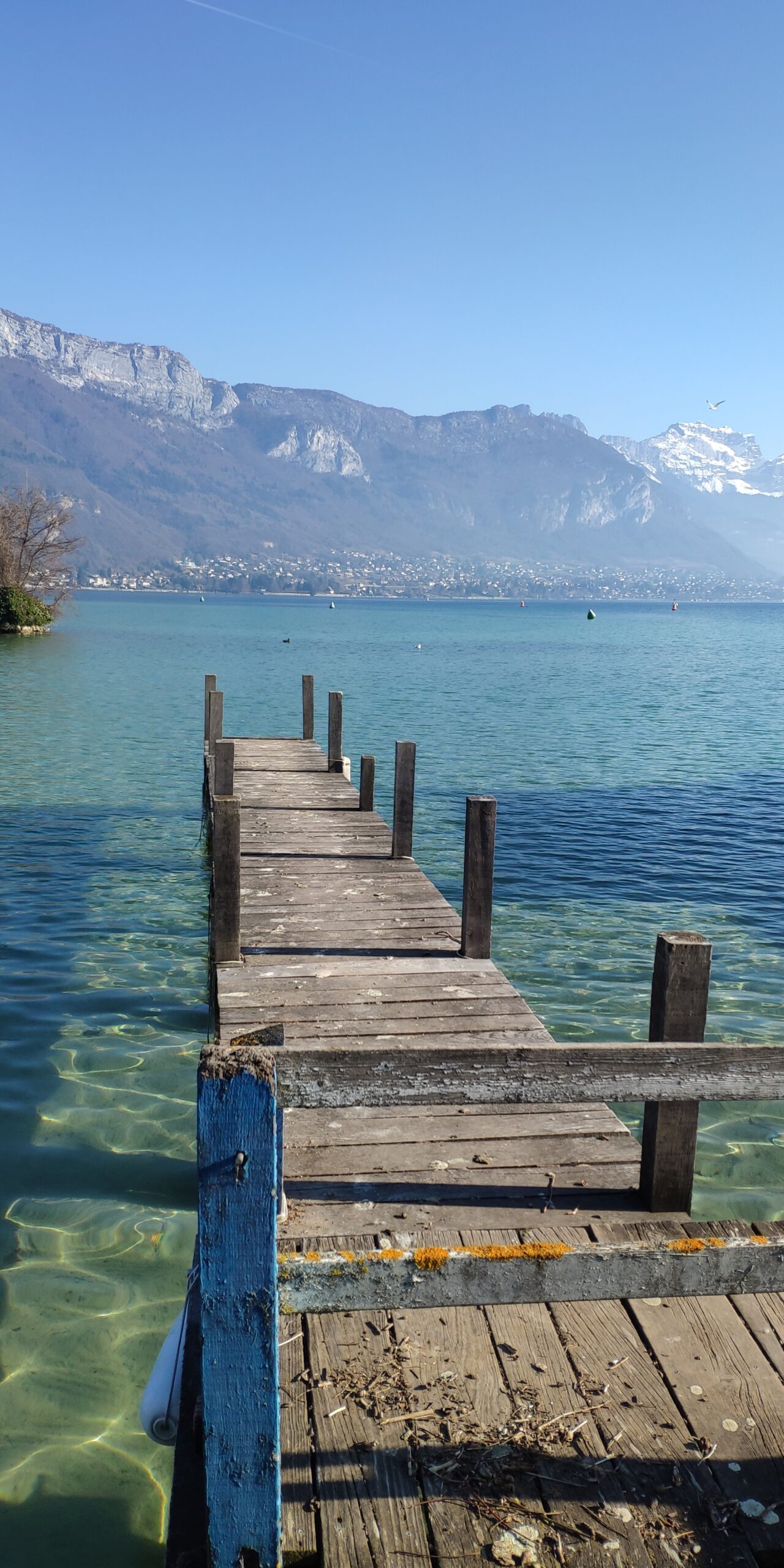 Ponton en bois avançant dans l’eau claire et turquoise du lac d’Annecy.
