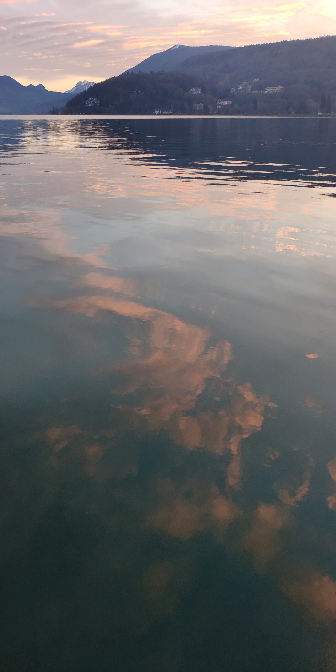 Nuages roses reflétés dans les eaux sombres du lac d’Annecy.