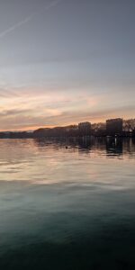 Reflets roses et argentés sur le lac devant la ville d’Annecy.