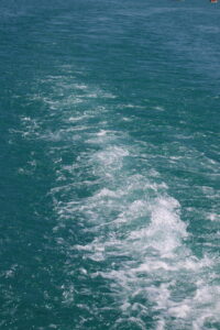 Sillage blanc dans l’eau turquoise du lac d’Annecy.