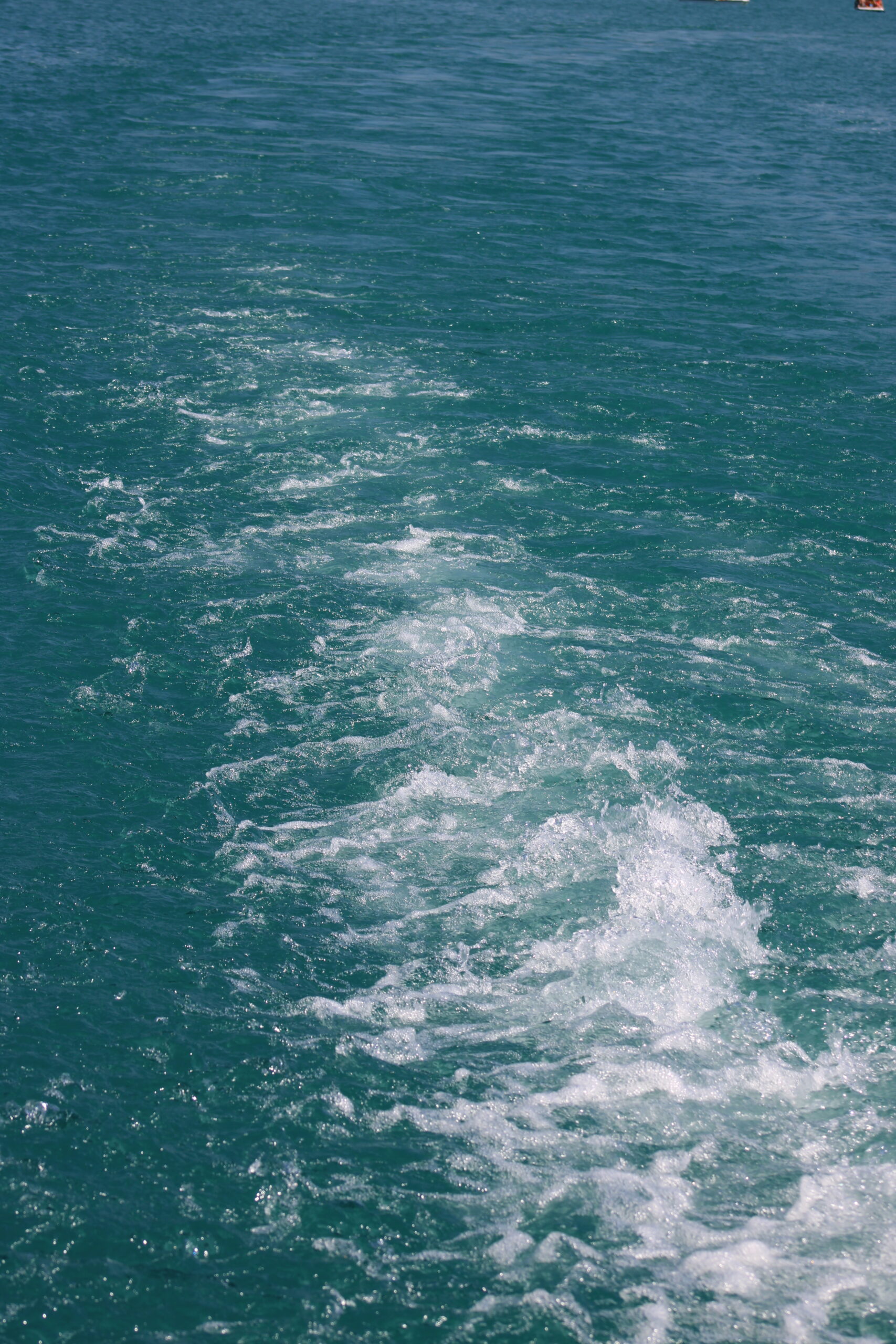 Sillage blanc dans l’eau turquoise du lac d’Annecy.