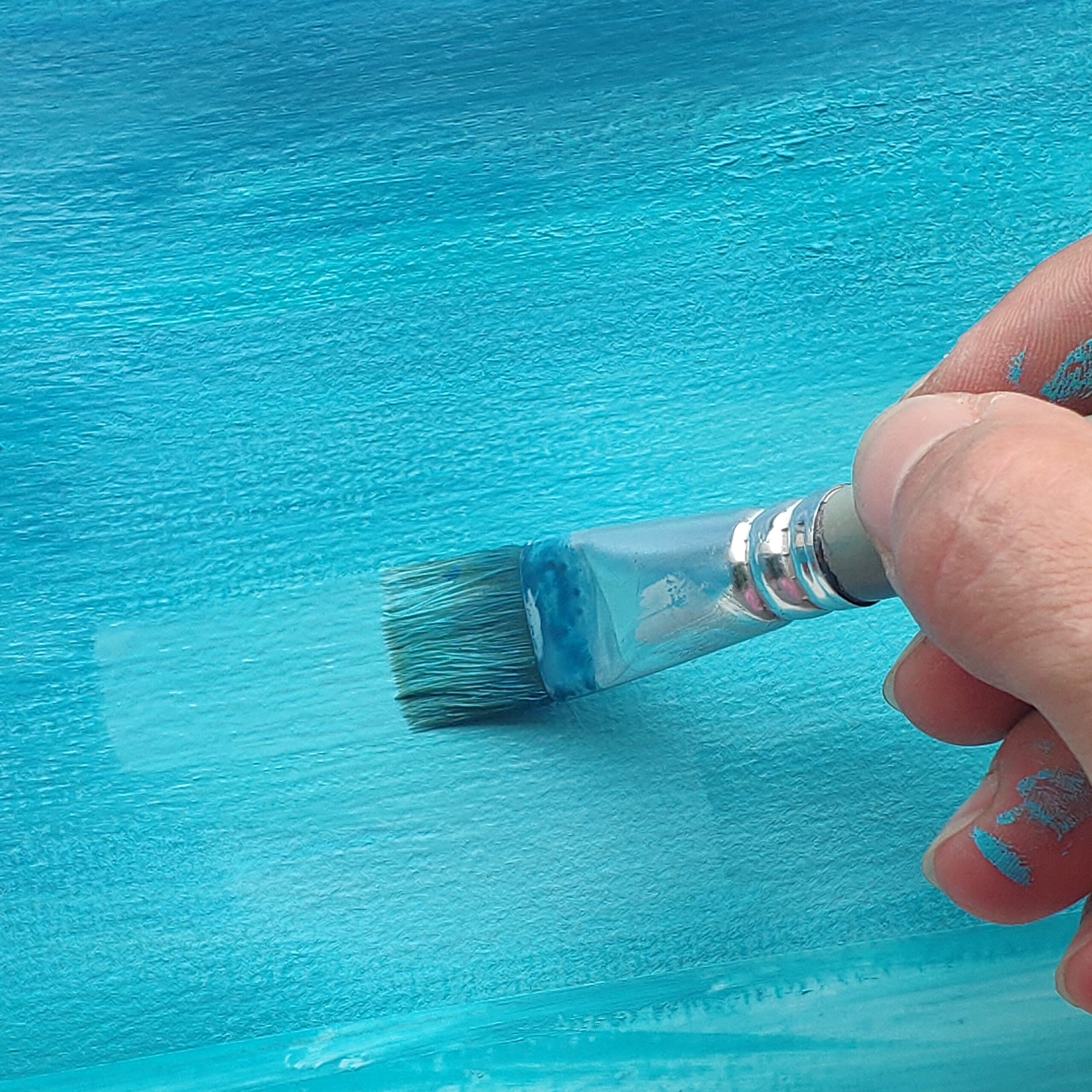 Pinceau appliquant une peinture turquoise inspirée du lac d’Annecy.